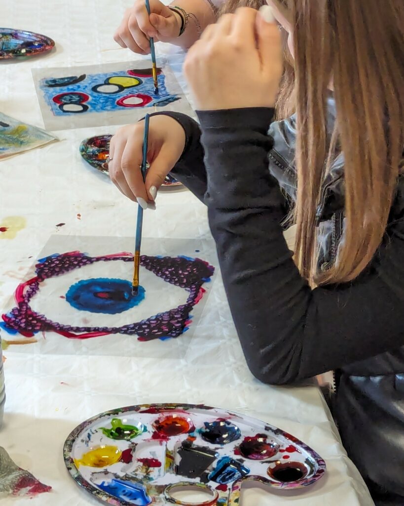 Des élèves sont en train de peindre des diapositives grand format lors d'un atelier.
